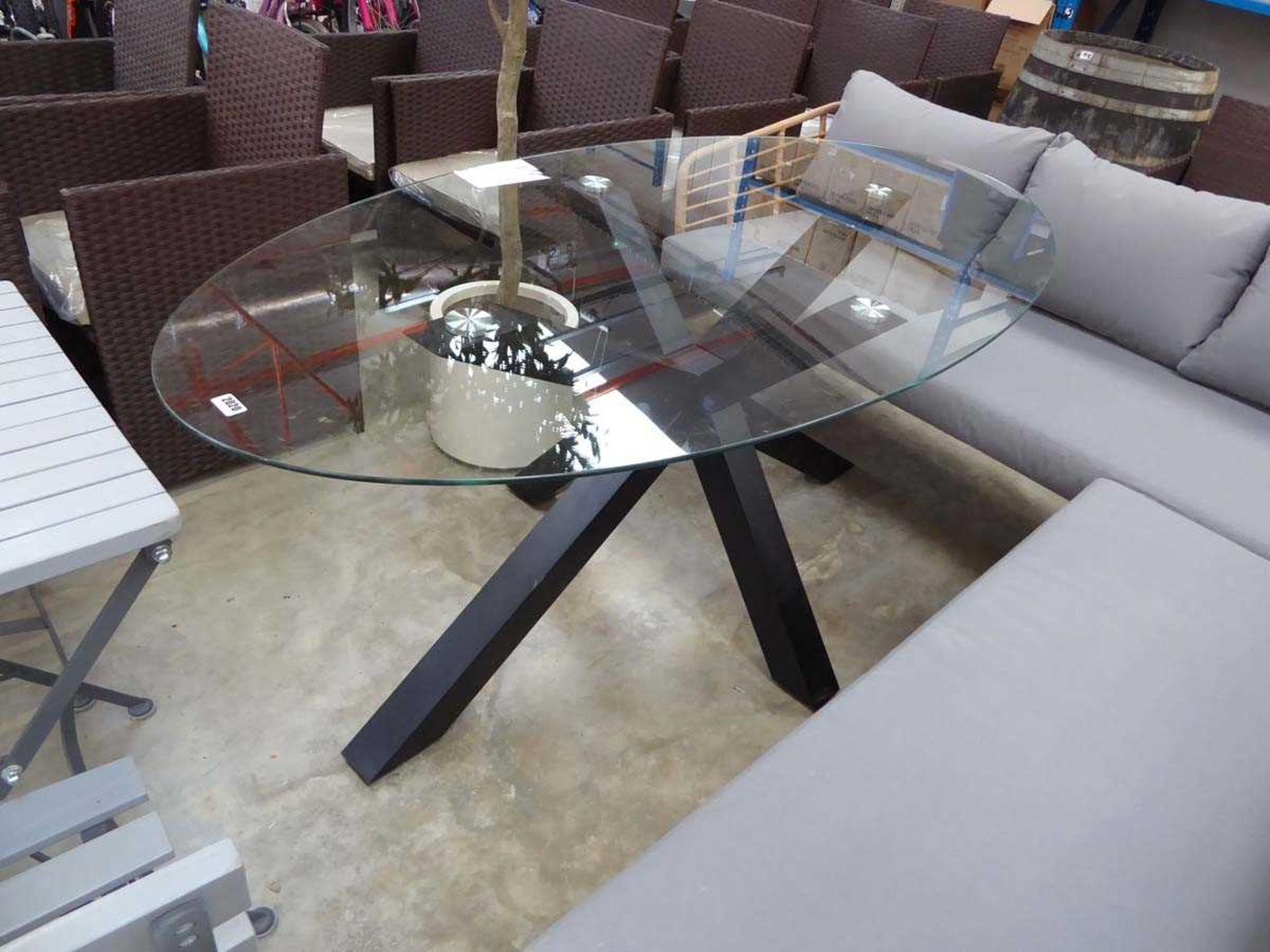 Oval glass topped dining table on black crisscross support
