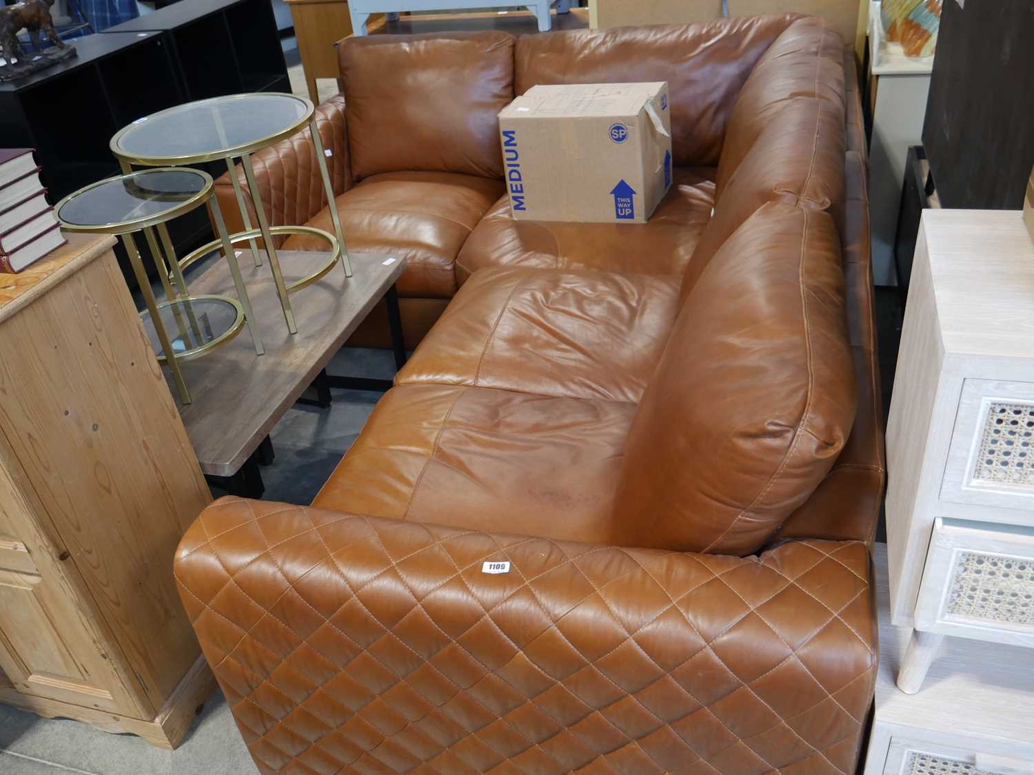 Tan corner sofa with diamond stitched arms together with a box containing the legs