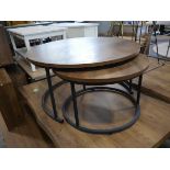 Nesting pair of circular hardwood finished coffee tables on black metal frames