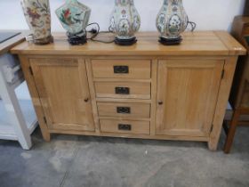 Modern light oak sideboard with 4 central drawers and 2 cupboards Some water damage to side Some