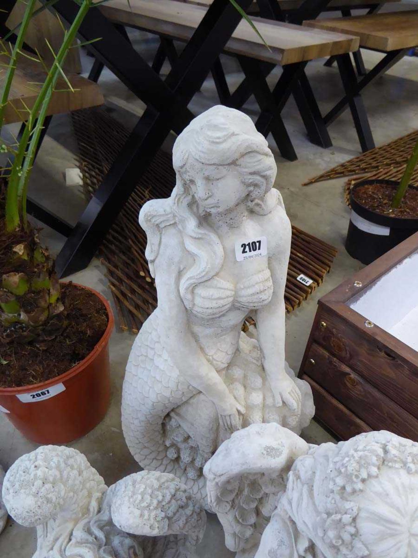 Concrete figurine of mermaid sitting on rock