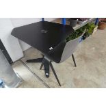 Black corner shaped desk with central power port together with grey soft cushioned chair