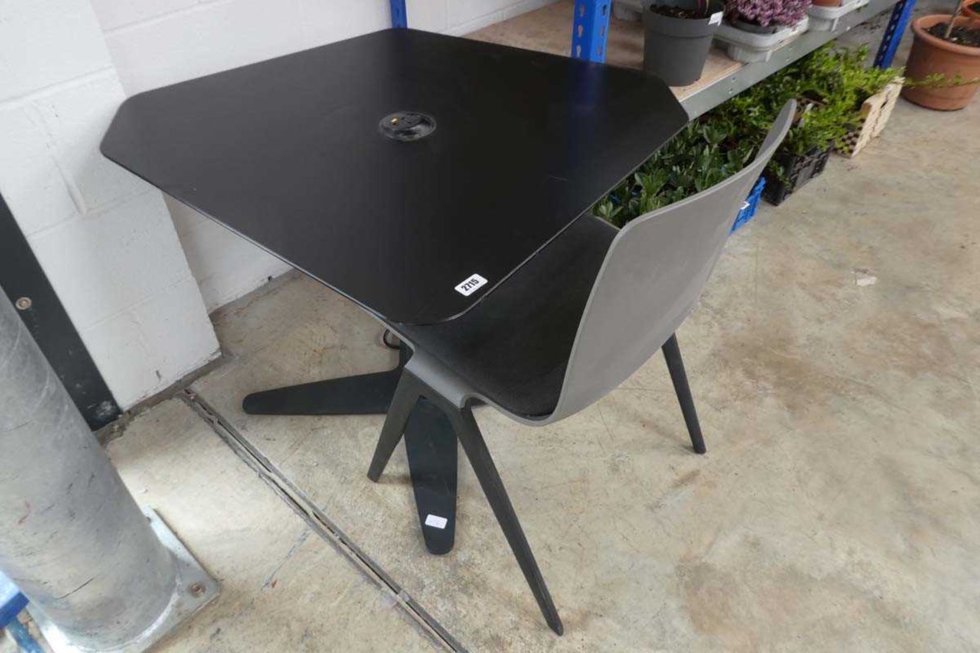 Black corner shaped desk with central power port together with grey soft cushioned chair