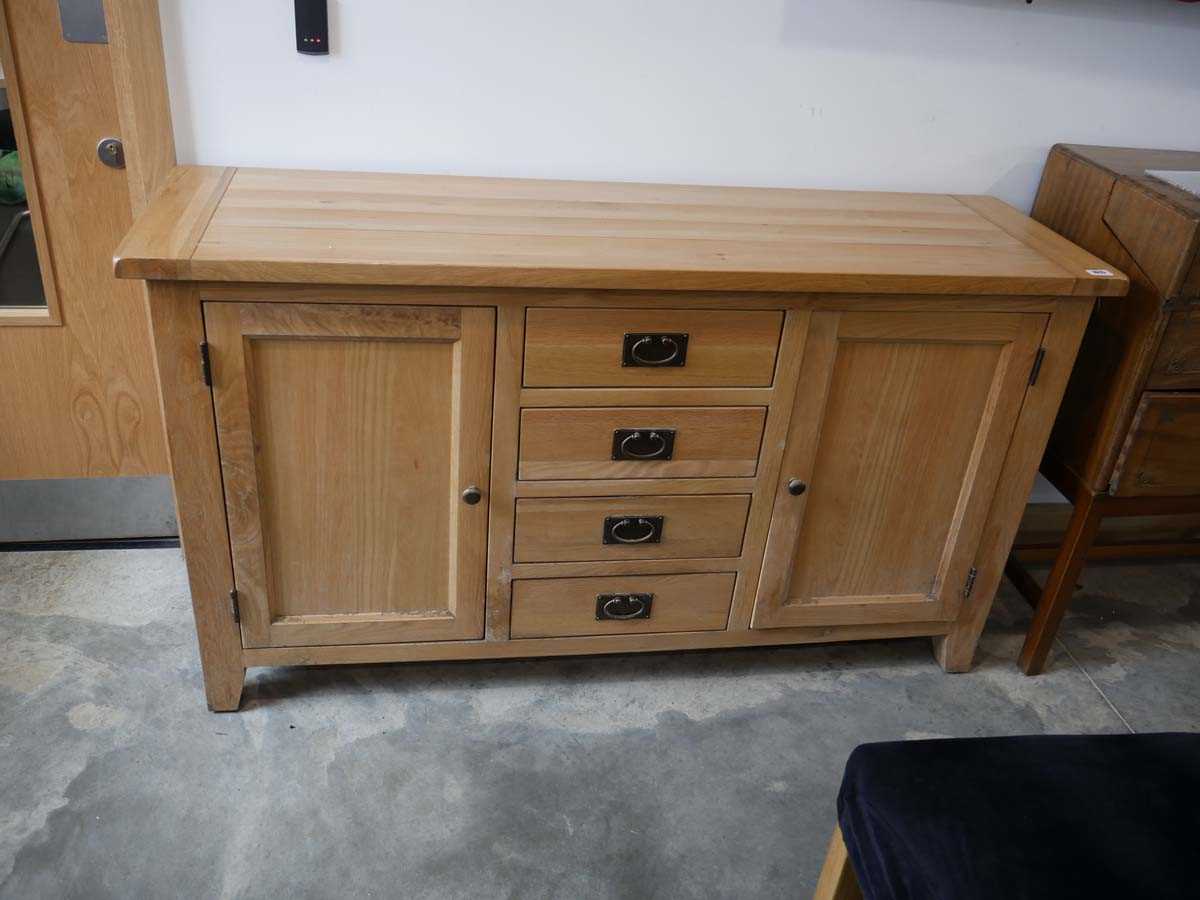 Modern light oak sideboard with 4 central drawers and 2 cupboards Some water damage to side Some