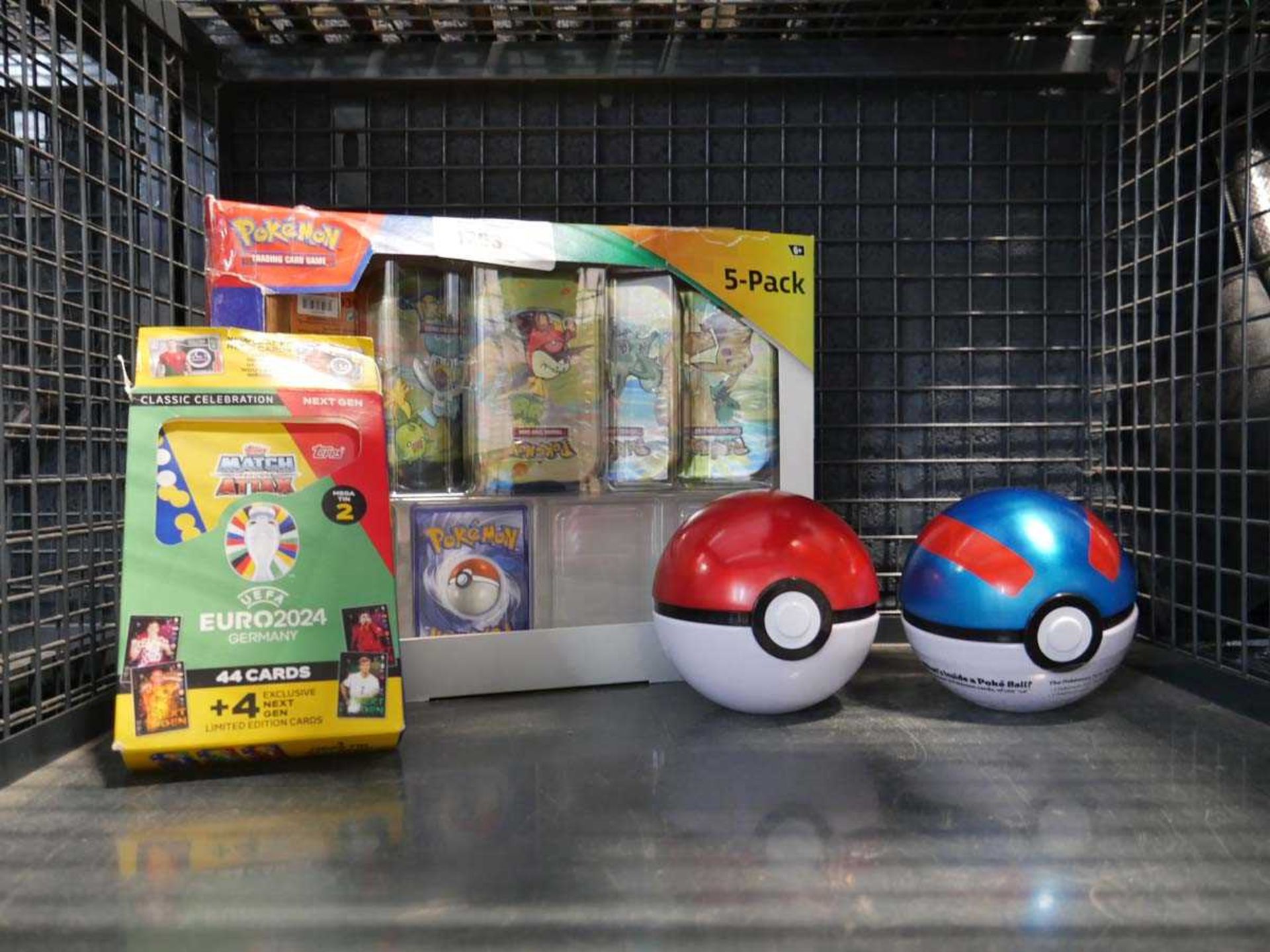 +VAT Cage containing various Pokémon card tins, 2 pokéballs and Match Attax Euro 2024 mega tin