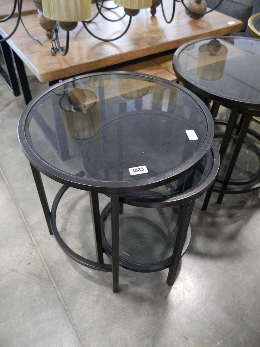 Nesting pair of black metal framed circular occasional tables with glass surfaces