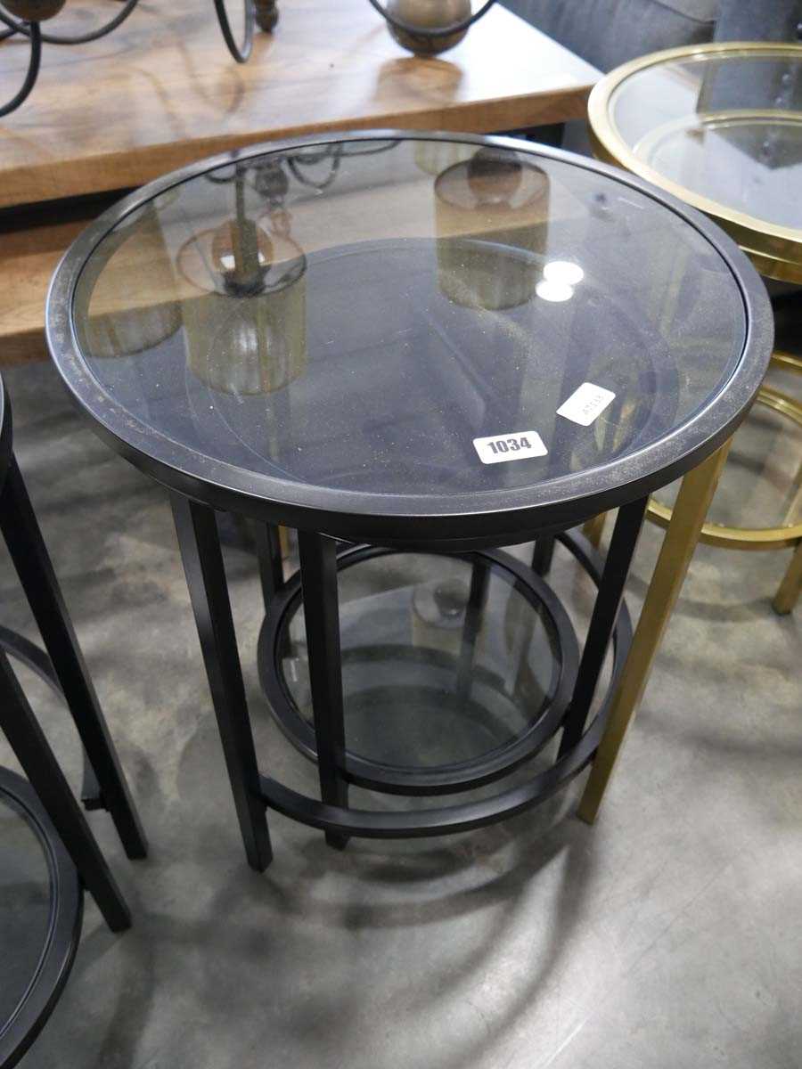 Nesting pair of black metal framed circular occasional tables with glass surfaces