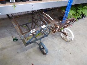 Pair of weathered wrought iron decorative planters in the form of wheelbarrows