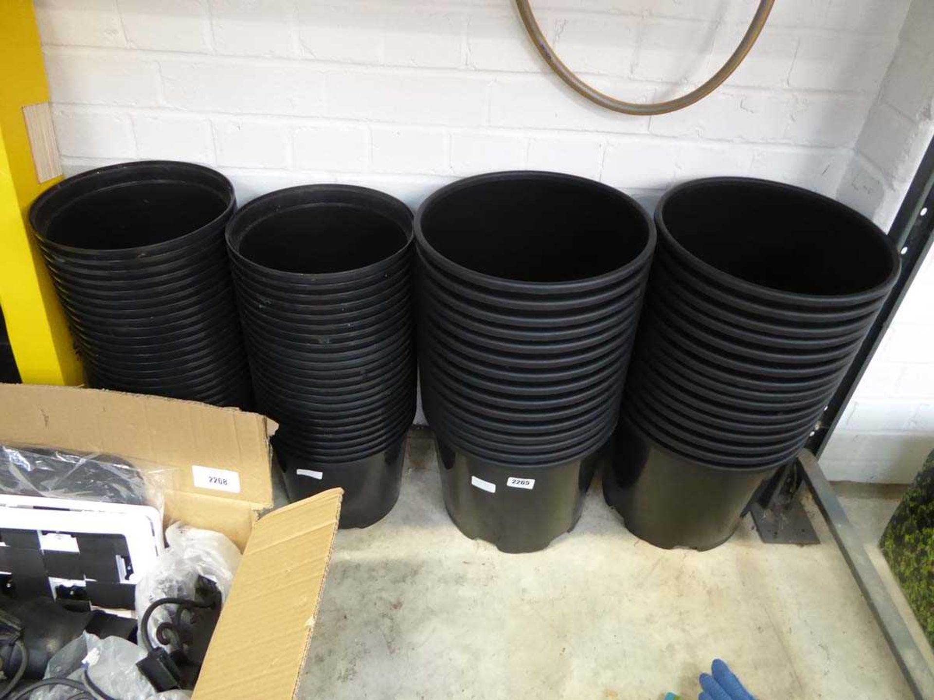 4 stacks of various size black plastic garden pots