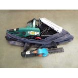 Bag containing green electric chainsaw and small hedgecutter