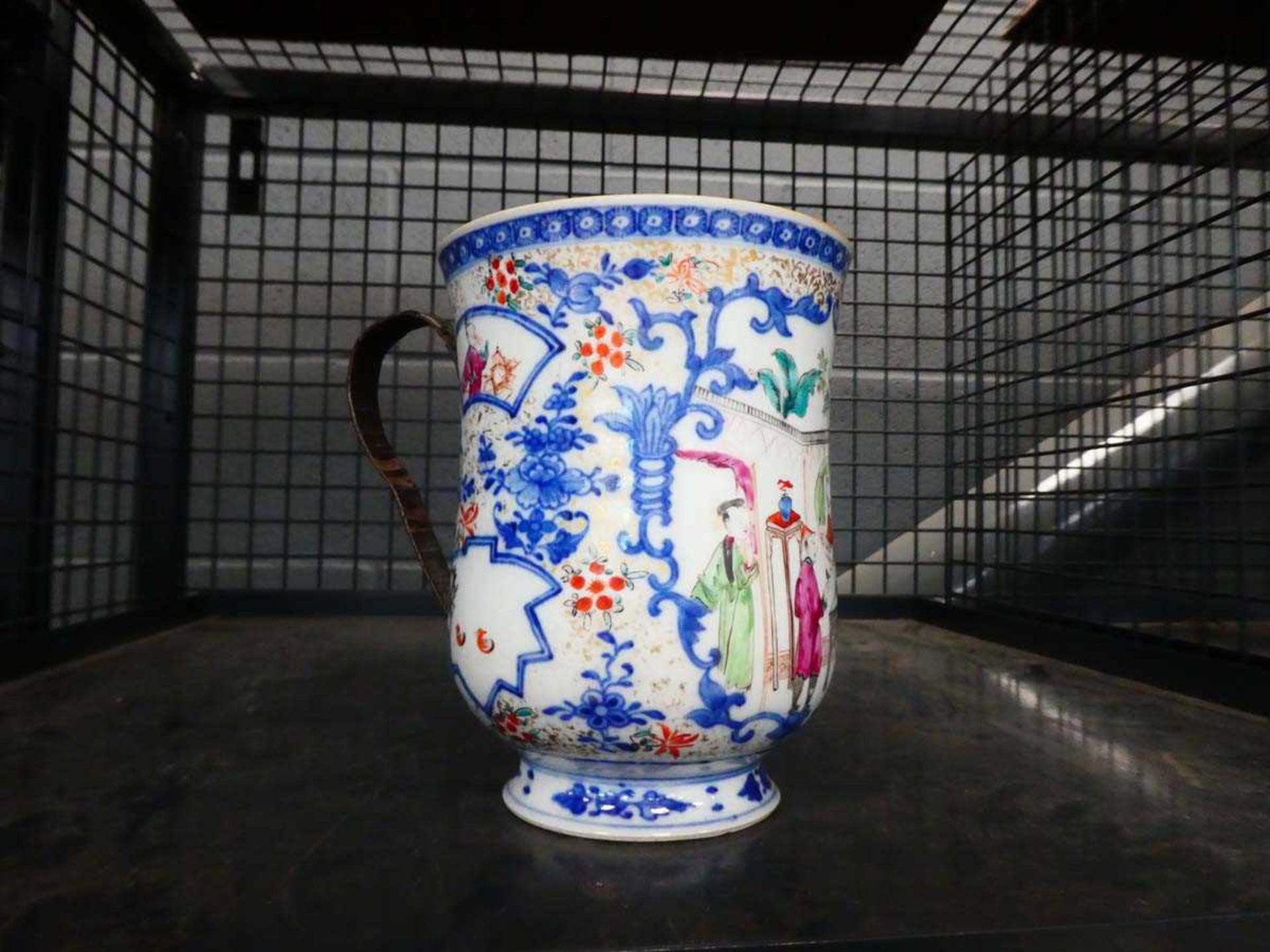 A Chinese Export mug of oversized proportions decorated with figures at leisure within blue and
