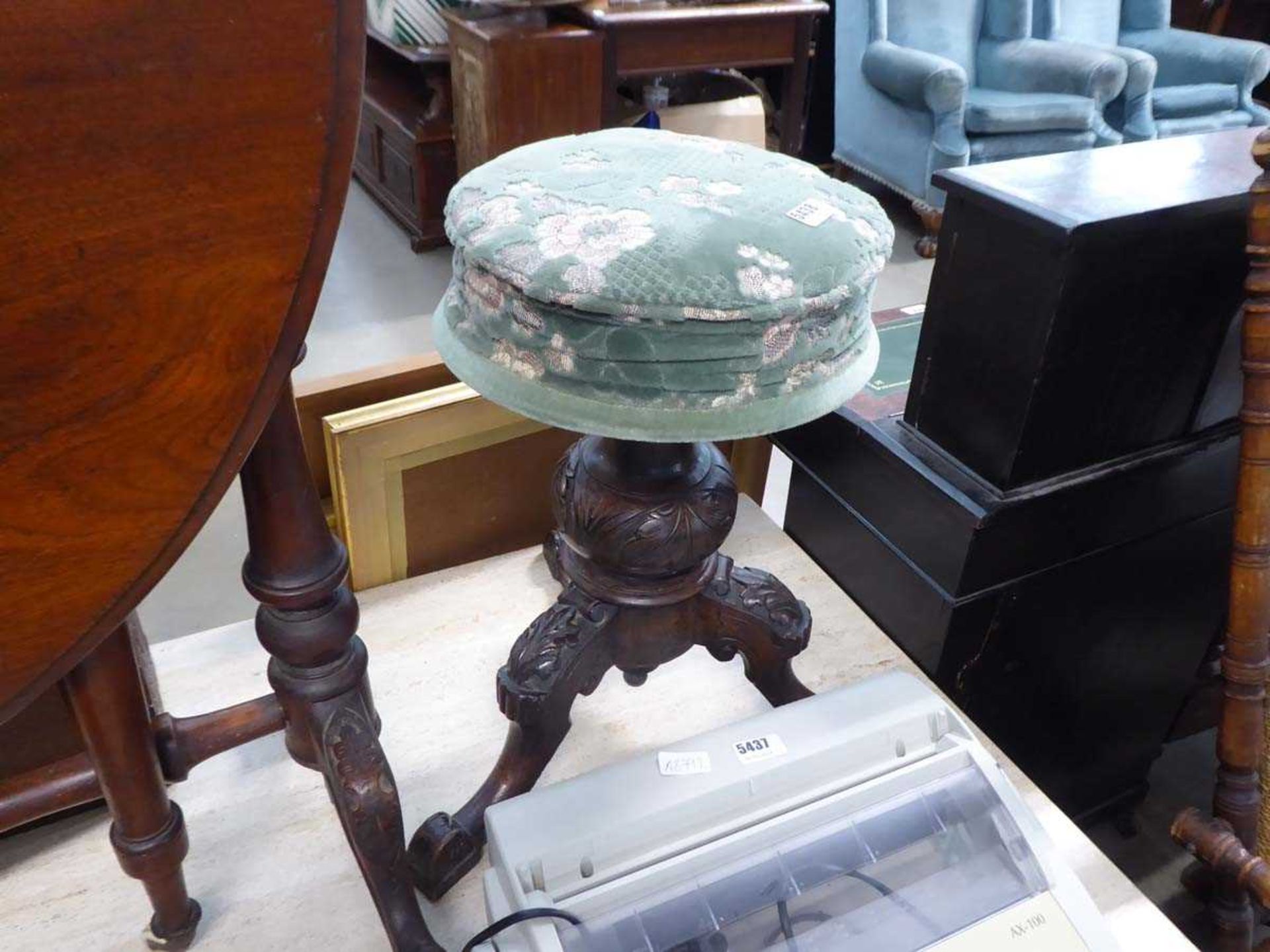 Heavily carved piano stool with green floral fabric