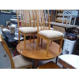 Circular teak extending dining table on tapered supports with 4 matching chairs with brown