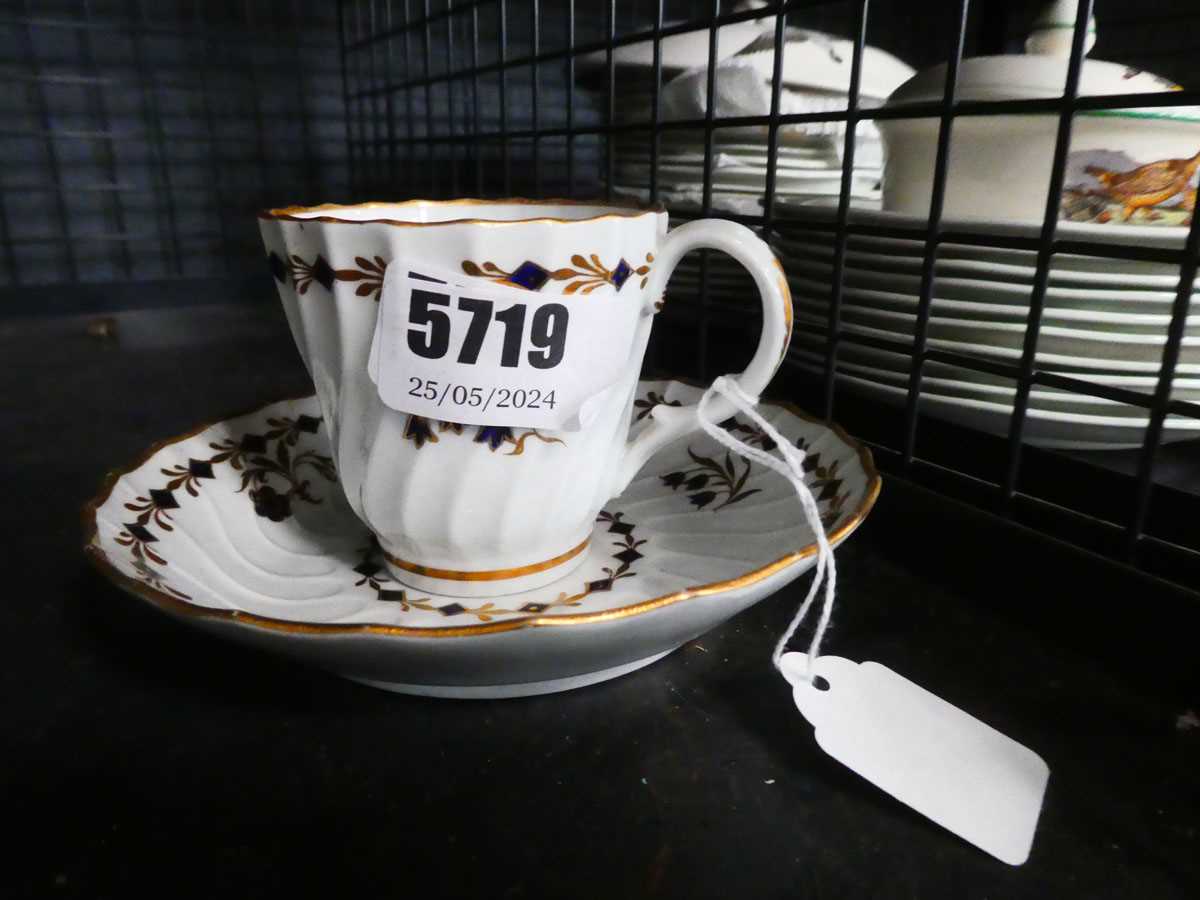 A 19th century tea cup and saucer dish, gilt decorated with a band of stylised blue flowers,