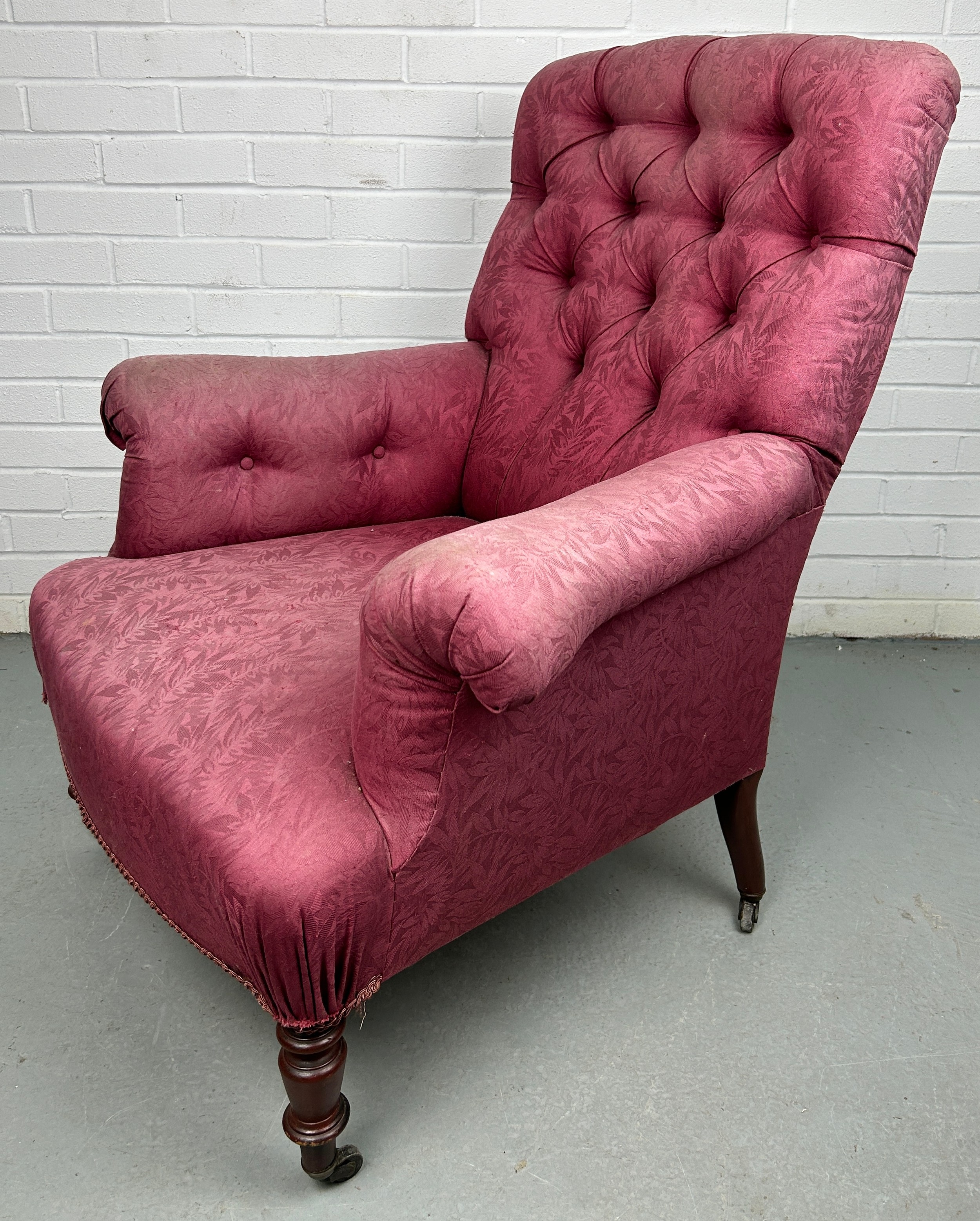 A VICTORIAN BUTTON BACK ARMCHAIR IN THE MANNER OF HOWARD AND SONS, Upholstered in raspberry coloured