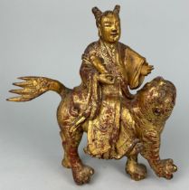 A CHINESE RED LACQUERED AND GILT WOOD FIGURE RIDING A LION, 21cm x 19cm