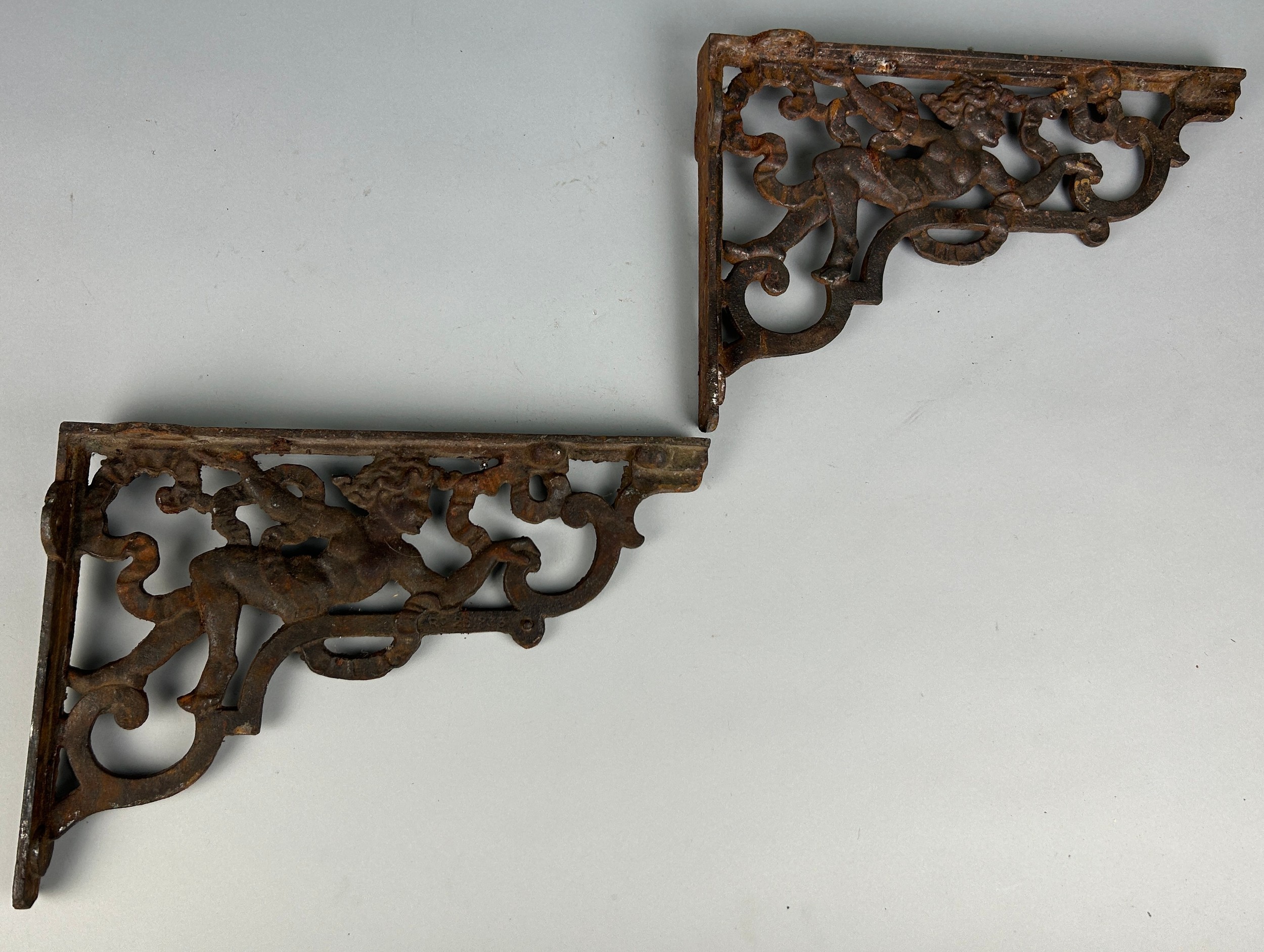 APAIR OF IRON CORNER BRACKETS WITH CHERUBS, 37cm X 25cm each