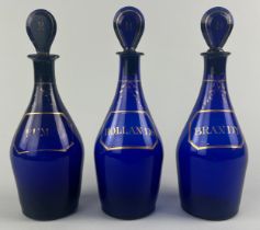 A SET OF THREE BRISTOL BLUE GLASS DECANTERS AND STOPPERS WITH GILT LABELS (3) Labelled for Rum,