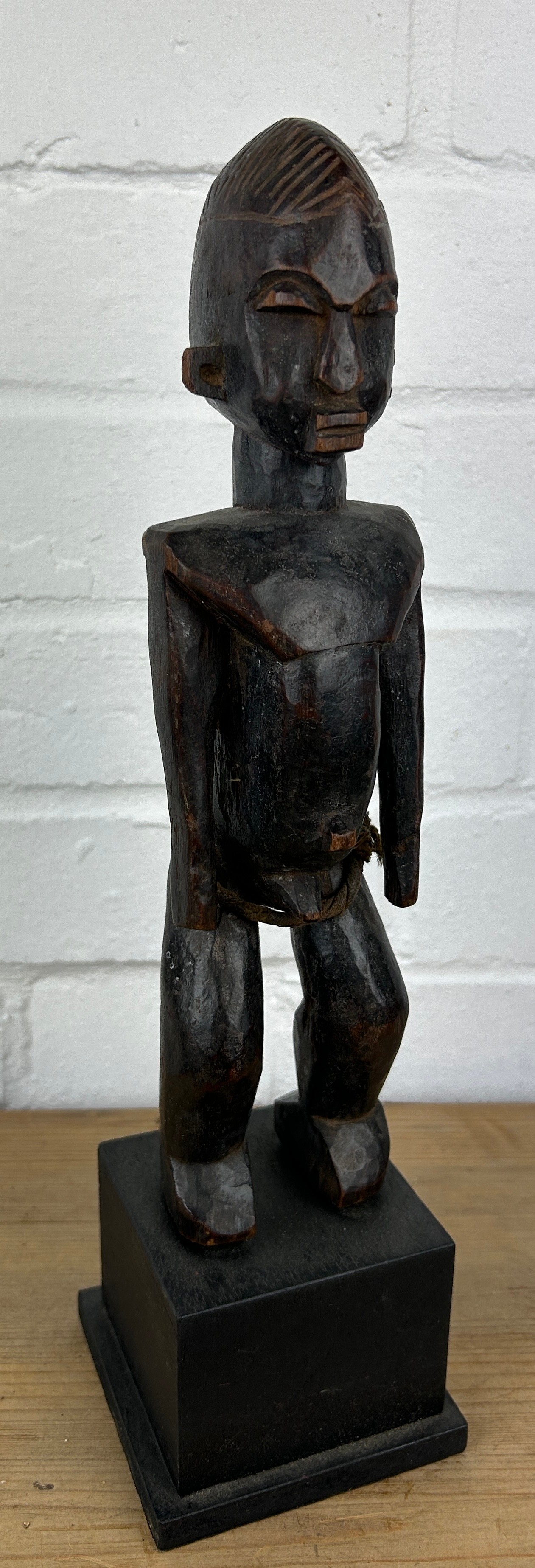 AN AFRICAN TRIBAL WOODEN MALE FIGURE, Mounted on wooden stand. 28cm H On stand 36cm H