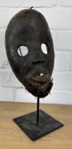 AN AFRICAN TRIBAL MASK MOUNTED ON STAND, 24cm x 14cm On stand 32cm H