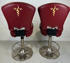 A PAIR OF POKER SWIVEL STOOLS UPHOLSTERED IN RED LEATHER WITH PICASSO STYLE FACES IN YELLOW TO BACKS
