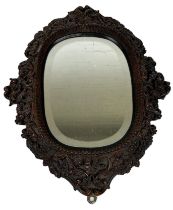 A CONTINENTAL OAK WALL MIRROR PROFUSELY CARVED WITH FLORA AND FAUNA, 56cm x 43cm