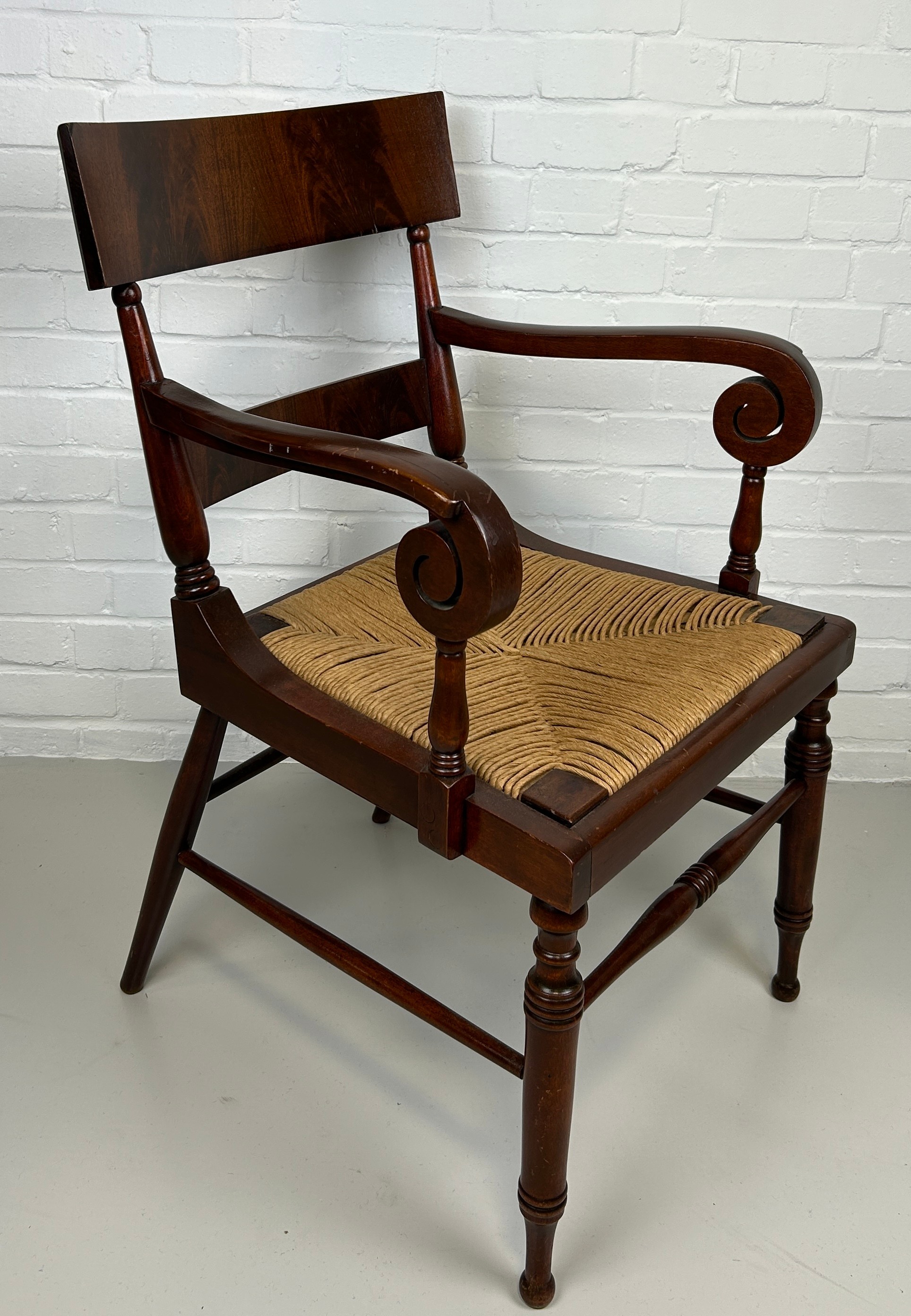 AN EARLY 20TH CENTURY ARMCHAIR OR DESK CHAIR, Flame mahogany with scroll arms and cane upholstered
