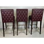 A SET OF THREE BAR STOOLS BY BEN WHISTLER UPHOLSTERED IN BURGUNDY LEATHER WITH WHITE BUTTON BACK,