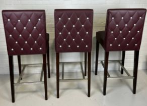 A SET OF THREE BAR STOOLS BY BEN WHISTLER UPHOLSTERED IN BURGUNDY LEATHER WITH WHITE BUTTON BACK,