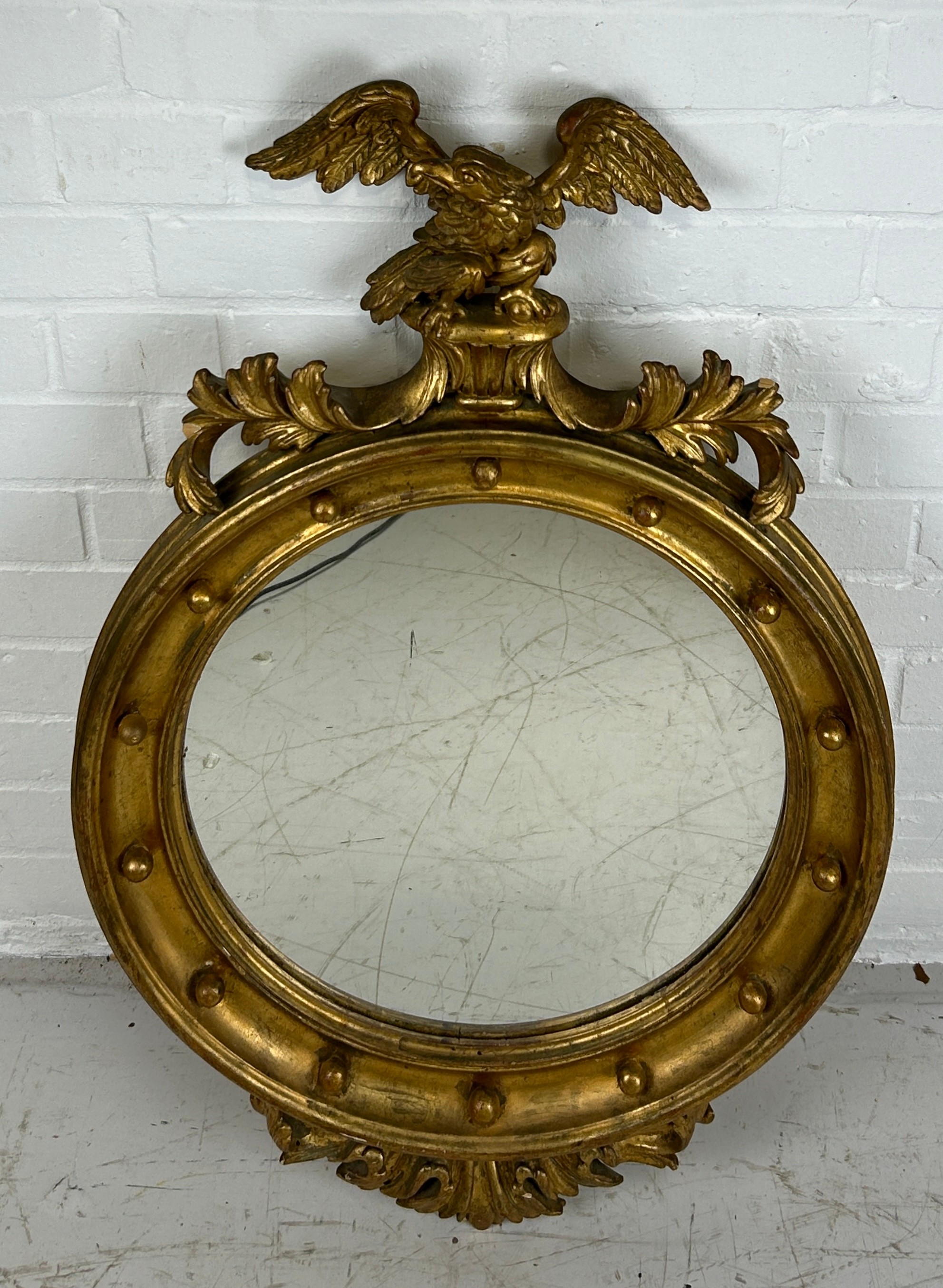 A GILT CIRCULAR WALL MIRROR WITH CARVED FRAME IN THE FRENCH IMPERIAL STYLE,