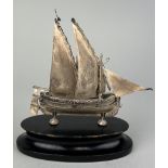 A SILVER JUNK SHIP MOUNTED ON STAND, 12cm x 12cm including stand.