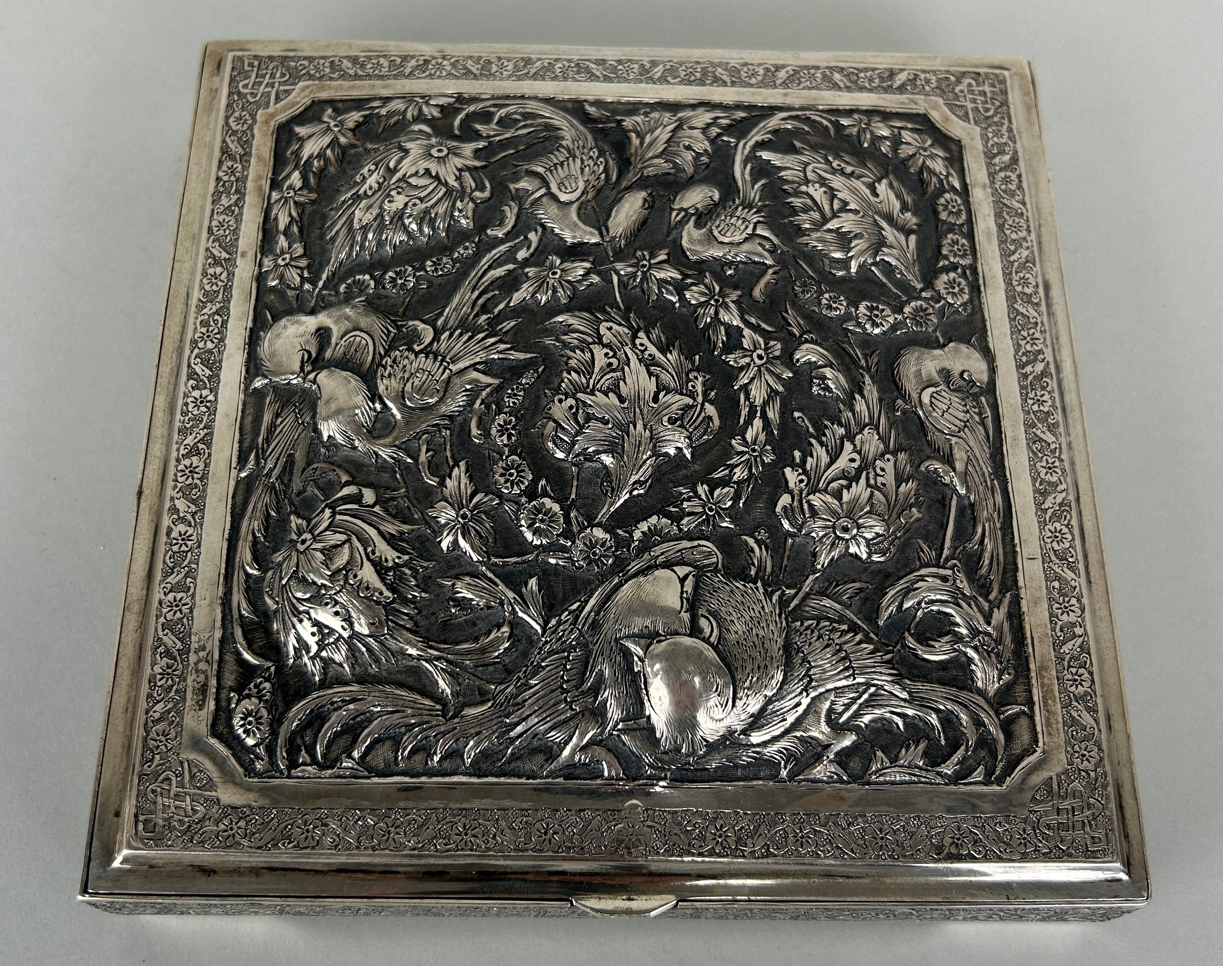 AN ANTIQUE PERSIAN SILVER BOX HAND CHASED REPOUSSE WITH FLOWERS AND BIRDS OF PARADISE, Hallmarked