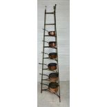 A GRADUATED SET OF SIX COPPER PANS ON GREEN PAINTED IRON STAND, Stand 182cm H Largest pan 22cm x