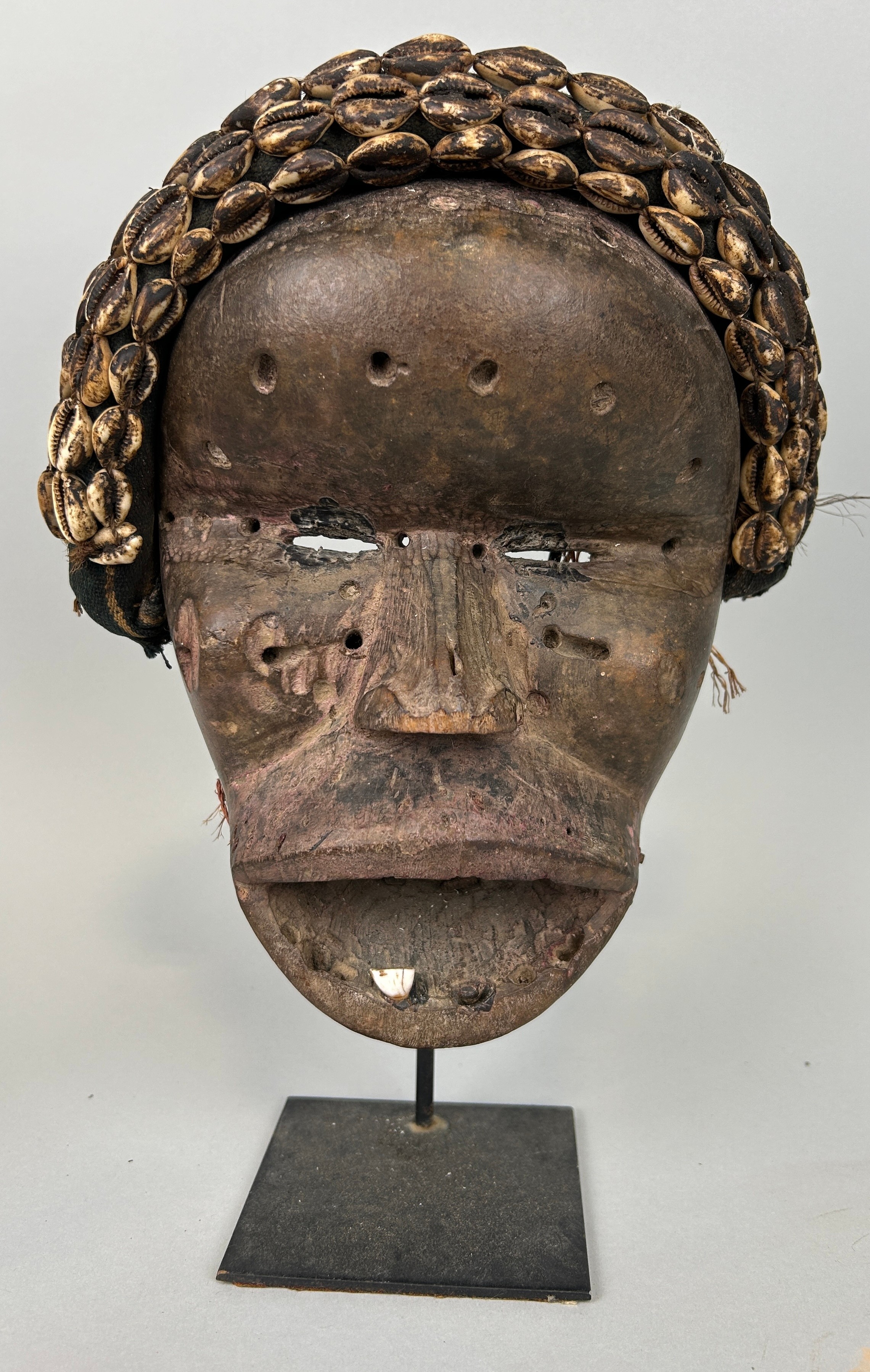 AN AFRICAN TRIBAL MASK WITH SHELL DETAIL, 26cm x 20cm Mounted on stand 32cm H