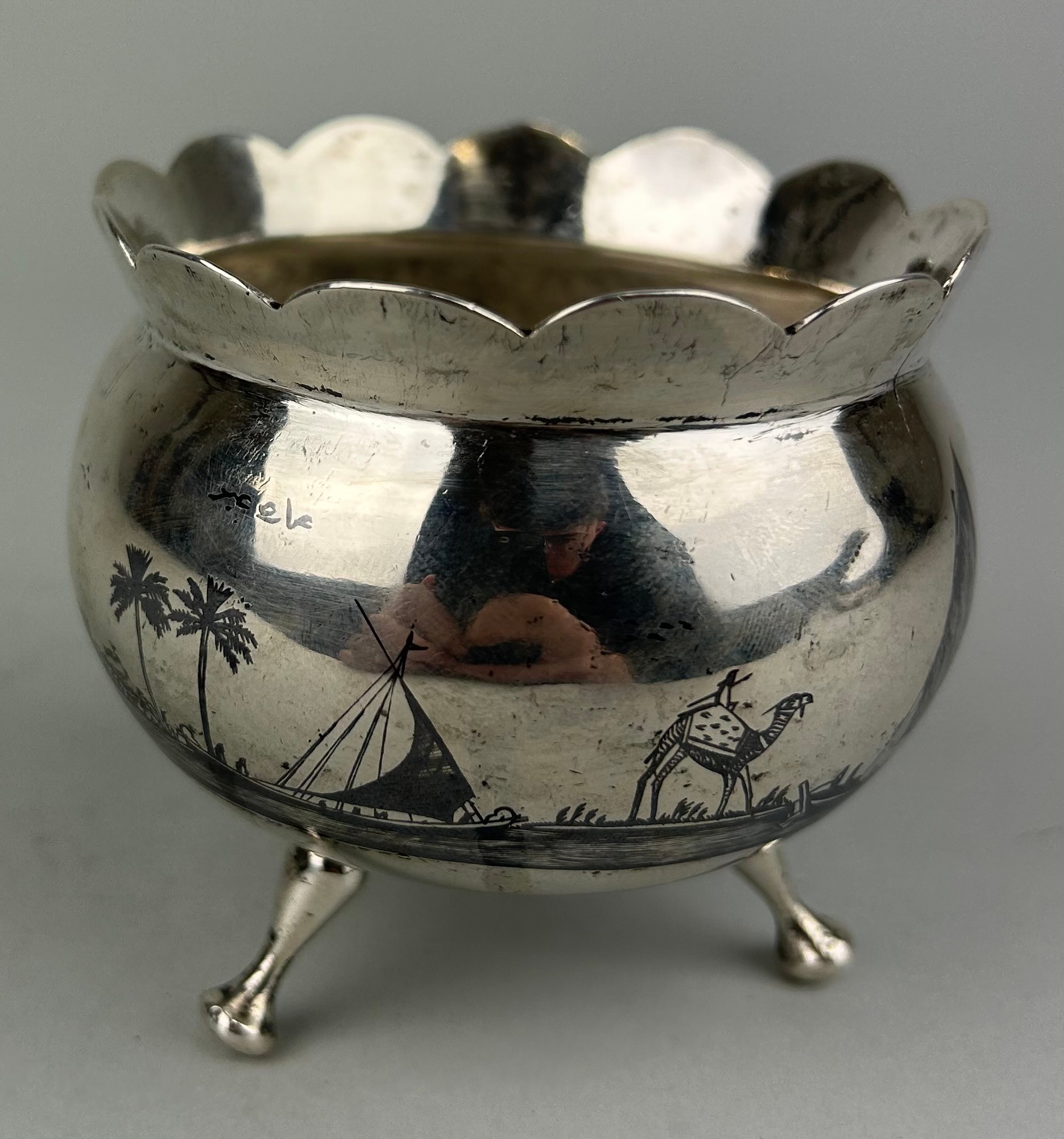 AN ARABIC SILVER BOWL ON TRIPOD STAND, Nielo decorated with palm trees. Signed to the side. Weight