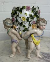 A DRESDEN PORCELAIN CANDLE CUP WITH FLOWERS ON THREE CHERUB SUPPORTS, 19cm x 15cm Crossed swords