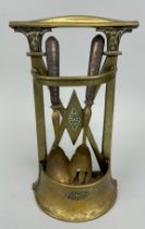 A BRASS SERVING SPOON AND FORK WITH SILVER HANDLES ON BRASS STAND