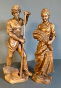 Two wooden carved rustic figures of a farmer and his wife tilling the fields