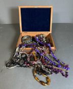 A carved wooden jewelry box with assorted necklaces and bracelets.