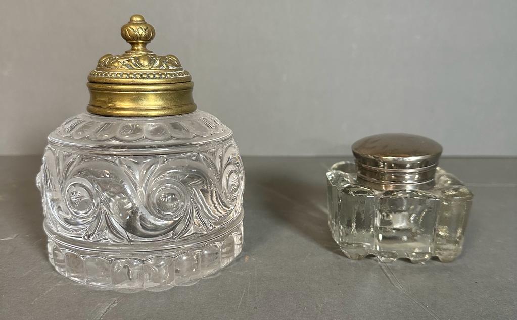 Two decorative ink wells, one with a brass lid and another with a white metal lid