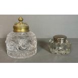 Two decorative ink wells, one with a brass lid and another with a white metal lid