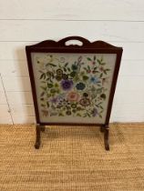 A glass fronted mahogany fire screen with a floral tapestry insert