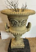 A garden urn planter with scrolling leaves and handles to side on a fluted stem to base (H82cm