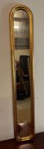 A long wooden framed gold painted oval hall mirror 114cm x 19cm