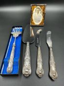A small selection of silver handled flatware and a silver framed photo frame.