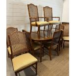 An oval two leaf bamboo effect dining table and eight wicker back chairs, two of them being