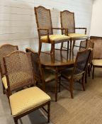 An oval two leaf bamboo effect dining table and eight wicker back chairs, two of them being