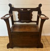 An oak Arts and Crafts hall stand bench with hinged lid to reveal storage and a carved back