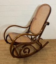 A scrolling Bentwood rocking chair with rattan back and seat