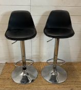 A pair of chrome based faux black leather bar stools